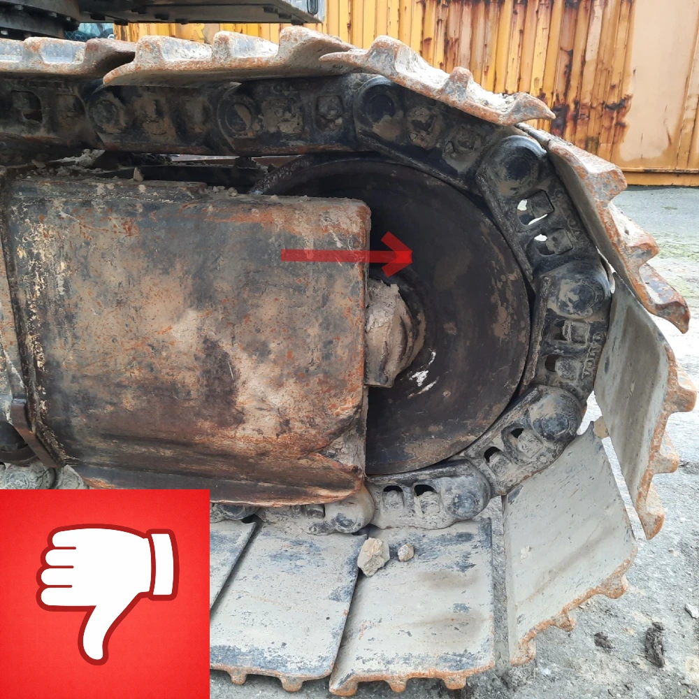 Bij een graafmachine met versleten rijwerk steekt het voorwiel uit het chassis.