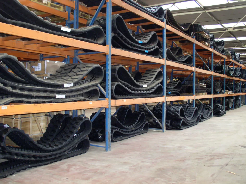 Magazijn met rekken gevuld met rubberen rupsen en rubber tracks voor graafmachines.