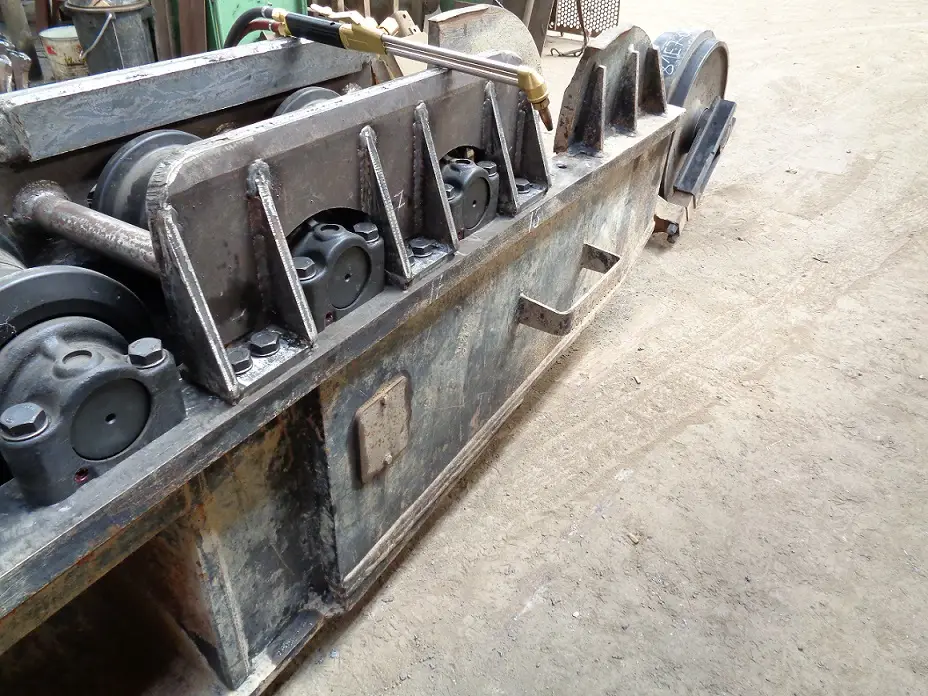 Onderwagen van een graafmachine die gedemonteerd wordt tijdens een rijwerkrevisie.