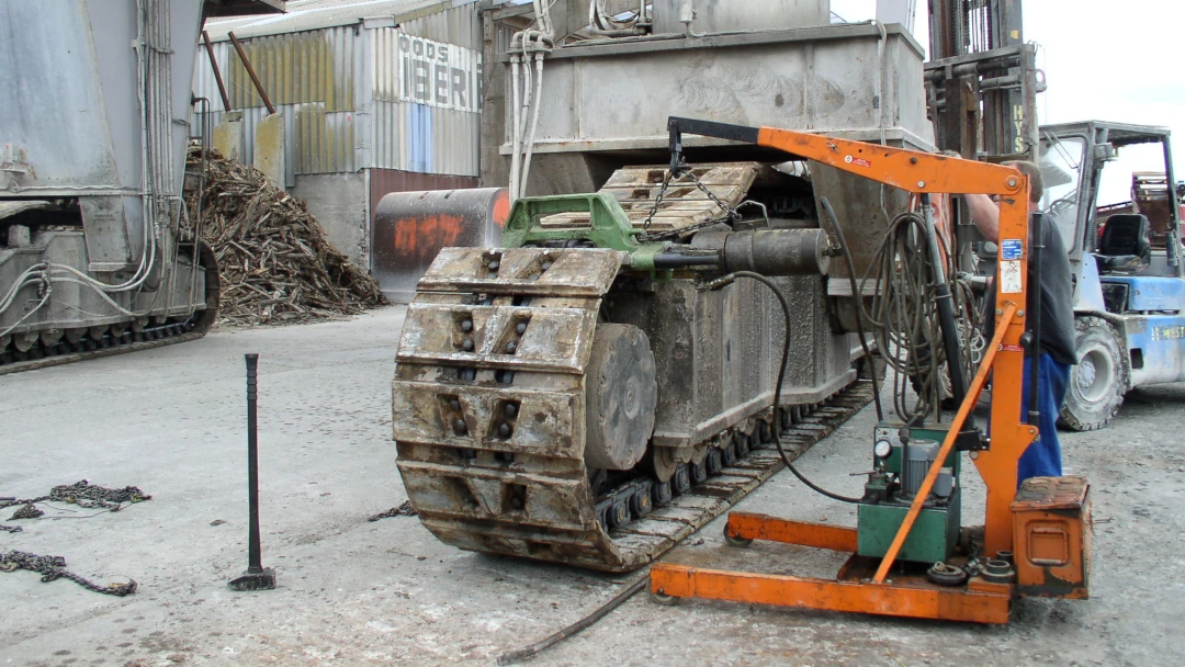 Een monteur van Janssentrack vernieuwt een schakel van het rijwerk van een graafkraan op locatie bij de klant.
