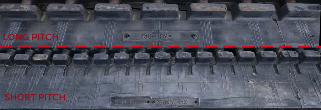 stuk van een rubberen rups of rubber track voor een graafmachine om het verschil aan te tonen tussen short pitch en long pitch rupsen.